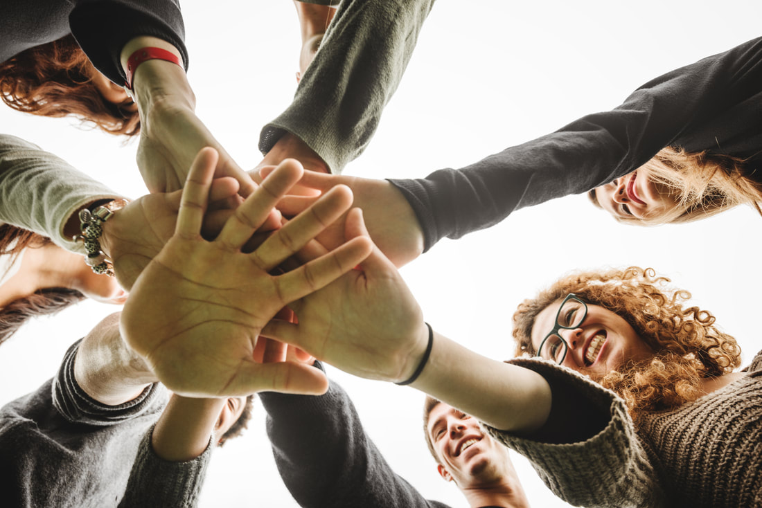 Group of people bringing their hands together in a huddle