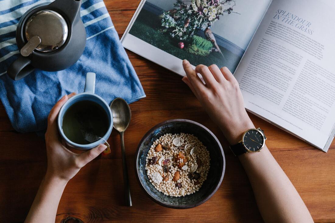 Picture of person's hands as they eat and drink healthy foods while reading