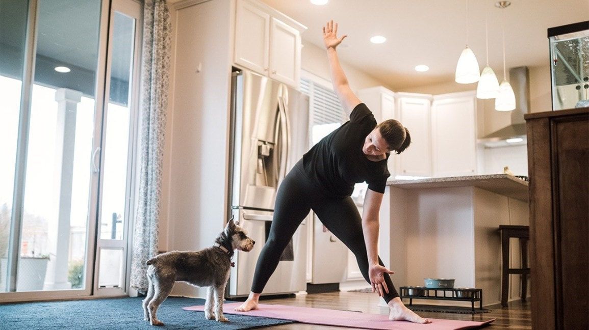 Person working out at home with a dog nearby